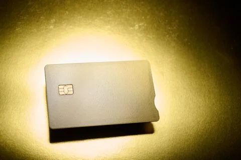 Closeup of a gold debit card with a microchip on a golden table Stock Photos