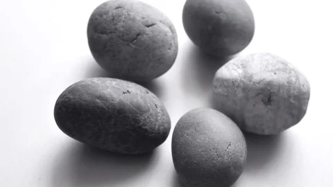 Closeup gray round stones spin on a light gray background. Ordinary plain Stock Footage 121564853