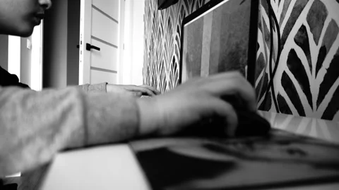 Closeup grayscale shot of a child playing Minecraft on a laptop behind a desk Stock Footage 236932143
