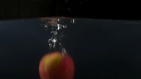 Closeup of green and red apples falling into water on the black backgrond slow Stock Footage 75790129