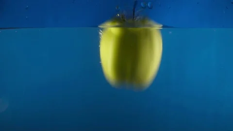 Closeup of green apple falling into water on the blue backgrond slow motion Stock Footage 75787436