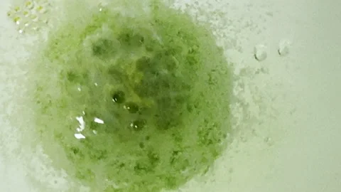 Closeup of green bath bomb spinning and fizzing bubbles Stock Footage 334053436