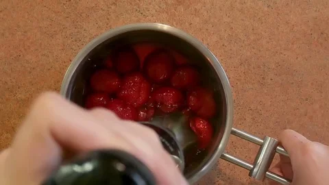 Closeup of grinding fruit with immersion blender in a stainless steel saucepan Stock Footage 84576335