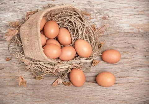 Closeup group of raw egg put in hemp bag and cover with dried leaves,on woode Stock Photos