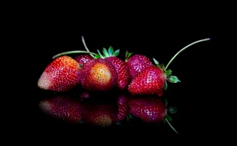 Closeup group of strawberries with reflection on ground Stock Photos