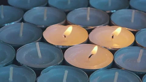 Closeup of a group of tea lights or waxine lights with three being lit Stock Footage 218600602