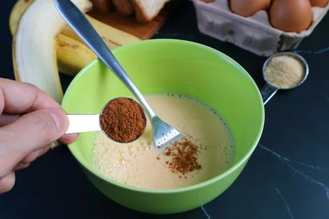 Closeup of Hand Adding Cinnamon Powder into the Mixture for Baking Pudding Stockfoto's