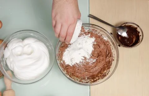Closeup hand adding flour egg white whipped chocolate Stock-Fotos