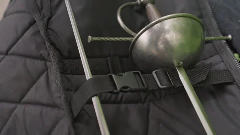 Closeup of hand adjusting strap on open padded bag with two crossed fencing Stock Footage 345850110