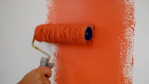Closeup hand of a builder paints a white wall with red paint using a roller Stock Footage 116760326