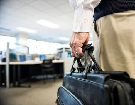 Closeup of a hand carrying a brief case in an office environment. Stock Photos