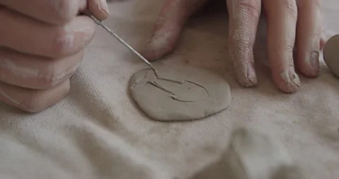 Closeup of hand carving a fish shape on soft clay using a sculpting tool Stock Footage 301617833