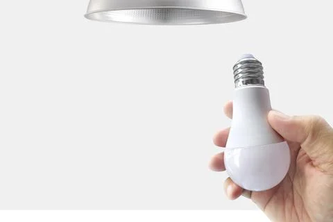 Closeup hand changing an electric light bulb Stock Photos
