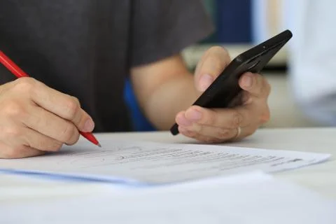 Closeup hand checking on a paperwork  freelance man writing with red pen on p Stock Photos