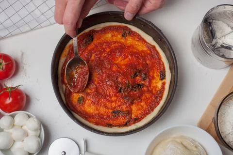 Closeup hand of chef adding tomato sauce on the pizza dough Foto stock