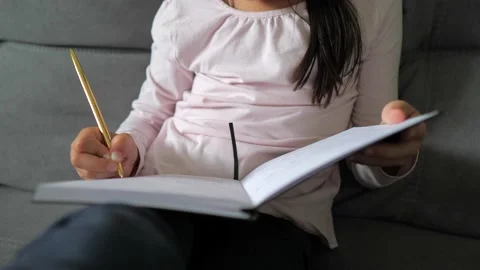 Closeup hand of child write in notebook with gold pen. Little kid girl student Stock Footage 215590796