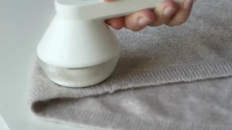Closeup of hand cleaning wool sweater from lint and pills. Fabric care process Stock Footage 331865024