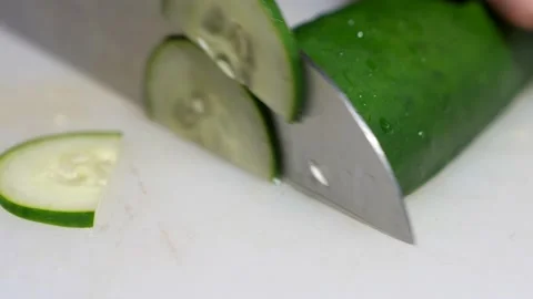 Closeup hand cuts cucumber on cutting board Stock Footage 141543432