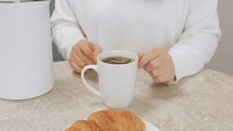 Closeup hand dipping tea bag into mug in kitchen, morning prep Stock Footage 328694317