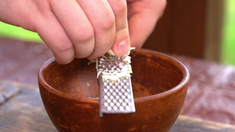Closeup of hand grating garlic with a small metal grater Stock Footage 248897627