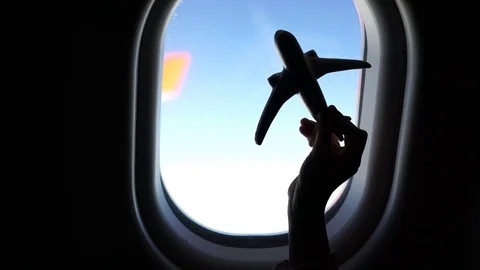 Closeup hand holding an airplane model toy background window at aircraft Stock Footage 76444910
