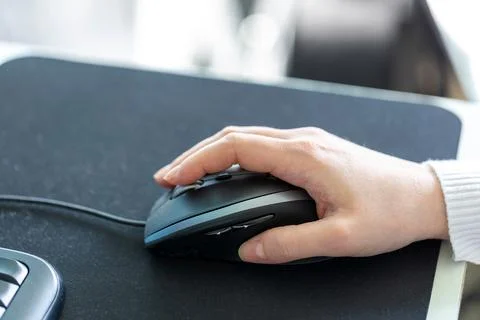 A closeup of a hand holding and using a optical computer mouse to navigate on Stock Photos