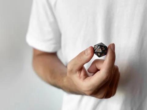 Closeup of hand holding a d20 dice against white background Stock Photos