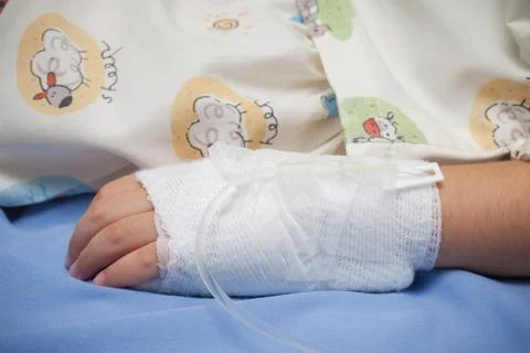Closeup hand of kid sick with The salt water tube on the bed in hospital Stock Photos