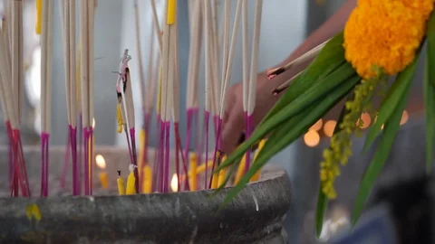 Closeup hand light the incense stick and candle with people praying in temple Stock Footage 125194309