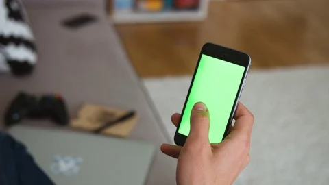 Closeup hand of man holds and touches a mobile phone with vertical green screen Stock Footage 77611461