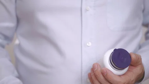 Closeup of the hand of a man pulling out an Omega 3 capsule Stock Footage 101085474