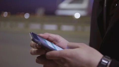 Closeup of the hand of a man using a mobile phone. A man stands on the street Stock Footage 105019427