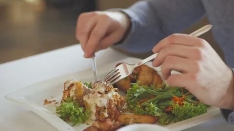 Closeup of the hand of a man who, with the help of a knife and fork, eats a Stock-Footage 104155165
