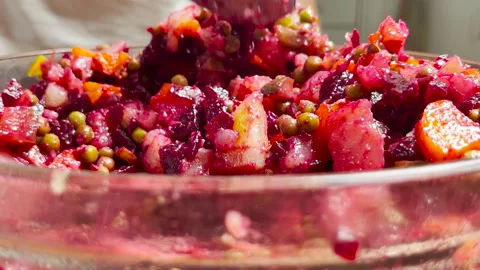 Closeup of a hand mixing vibrant vegetable vinaigrette salad with a spoon in a Stock Footage 311009885