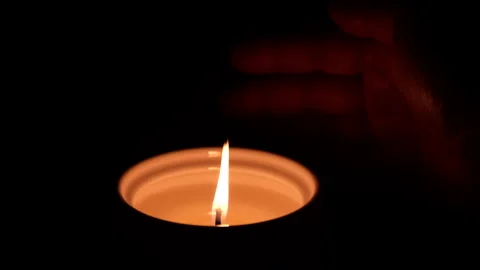 Closeup of hand moving close to a burning candle in dark background. Stock Footage 169921550