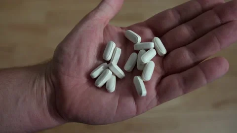 Closeup of Hand opening up to reveal a multitude of generic white pills Stock Footage 136493628