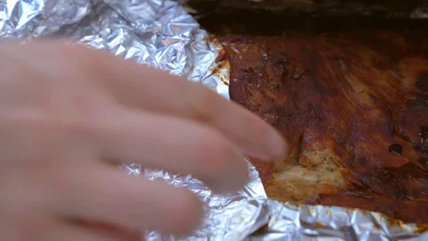 Closeup hand opens foil on rack of ribs Stock Footage 129859680