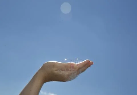 Closeup hand palm up holds soap bubbles on blue sky background Stock Photos