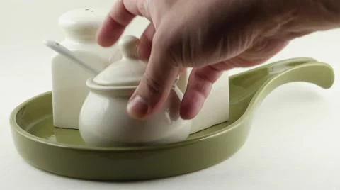 Closeup hand placing Ceramic salt and pepper dispenser and sugar bowl on a plate Video stock 68769361