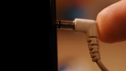 Closeup of hand plugging and unplugging headphones from jack on phone Stock Footage 120532219