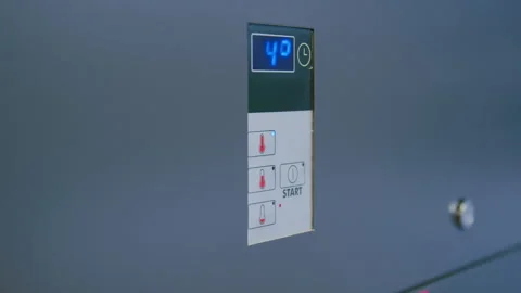 Closeup of a hand pressing buttons on a digital control panel, displaying a Stock Footage 329365933