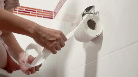 Closeup hand pulling toilet paper roll in holder for wipe Stock Footage 177752812