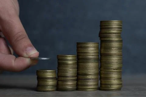 Closeup of hand put Coins to stack of coins,Concept Saving money. Stock Photos