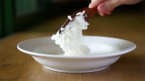 Closeup hand putting hot cooked rice on white dish Stock Footage 130486188