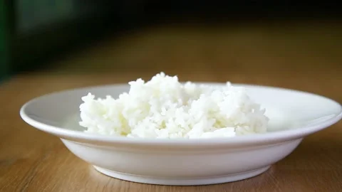 Closeup hand putting hot cooked rice on white dish Stock Footage 130486194