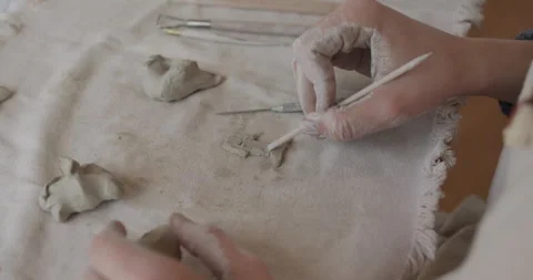 Closeup of hand sculpting a small fish shape from clay using wooden tools Stock Footage 301616906