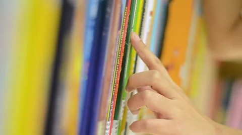 Closeup hand selecting book from a bookshelf Stock Footage 35859182