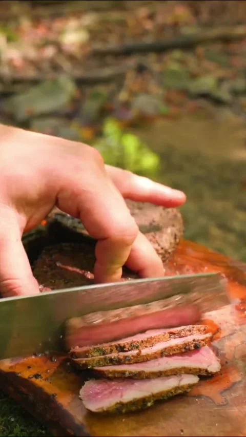 Closeup of a hand slicing a perfectly cooked mediumrare steak on a wooden board Stock Footage 336656794