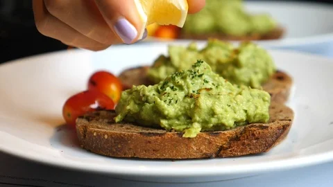 Closeup Of Hand Squeezes Lemon On Toast With Avocado. Breakfast, Healthy Food. Stockbeeldmateriaal 108421284