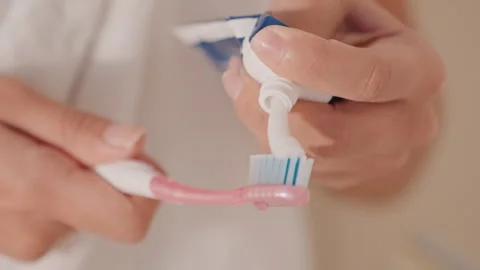 Closeup of hand squeezing paste onto brush in hotel bathroom. An individual in Stock Footage 331740148